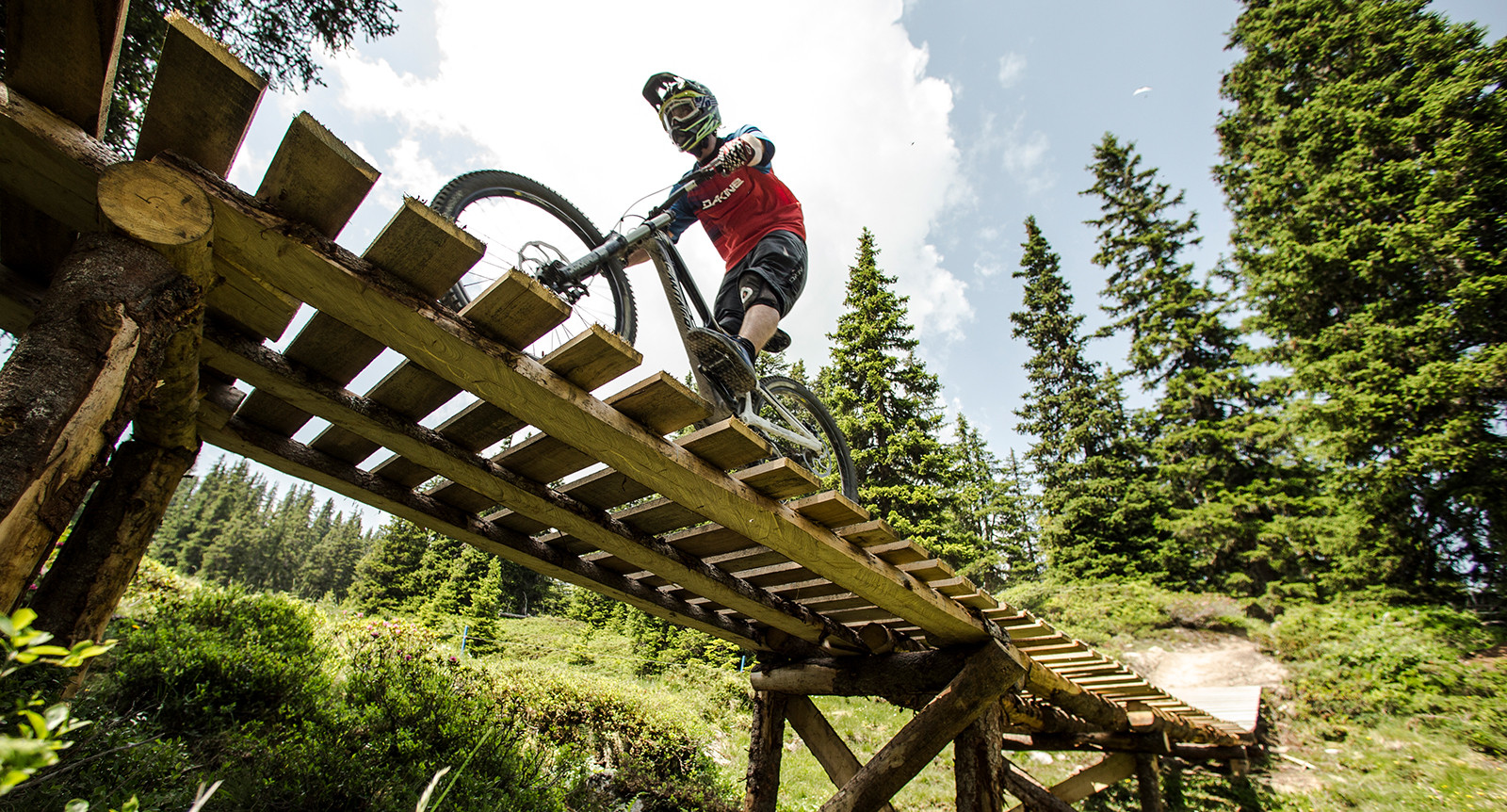 Mann fährt mit Mountainbike über eine Holzbrücke auf den Runcatrail in Flims Laax Falera